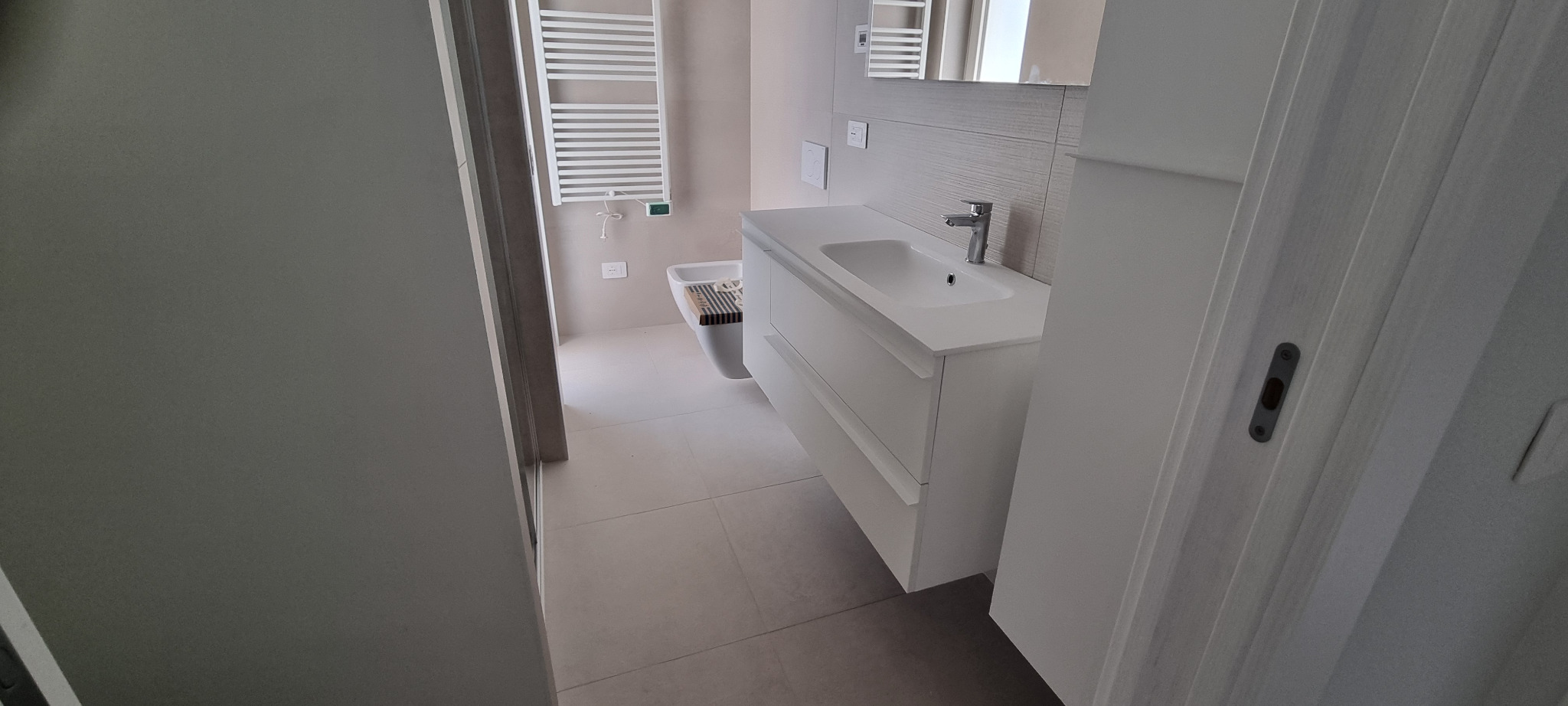 Bagno chiaro con mobile sospeso e rivestimento materico