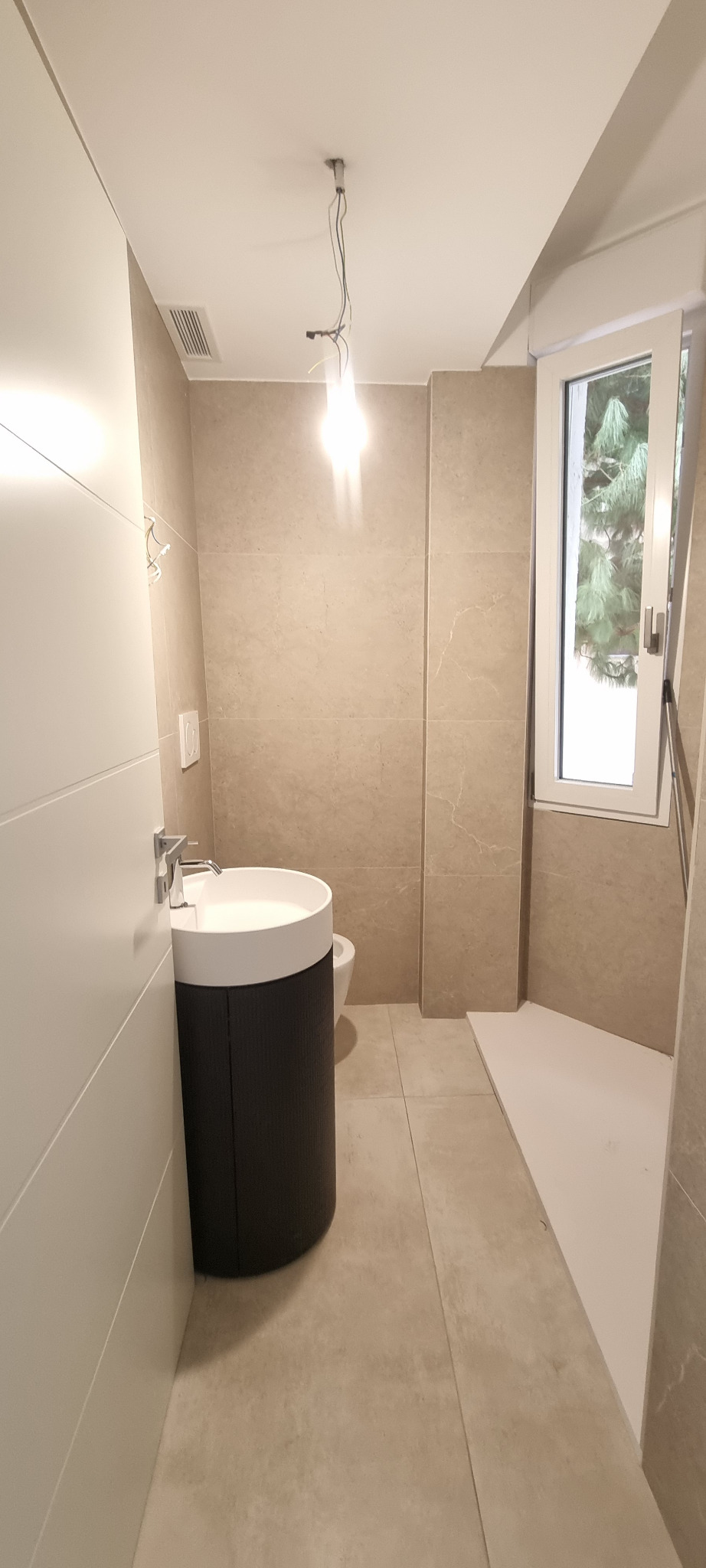 Bagno compatto con lavabo tondo e rivestimento in pietra