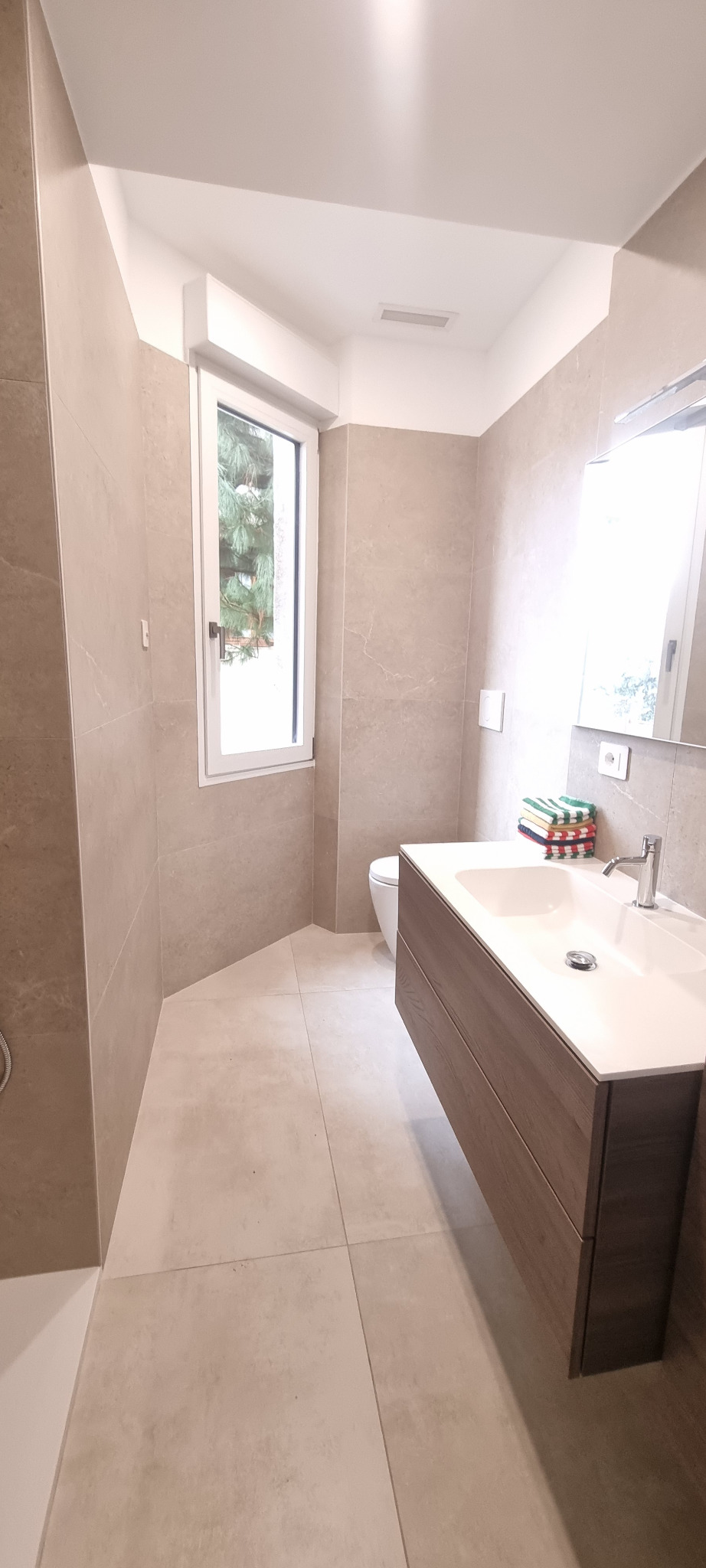Bagno contemporaneo in tonalità pietra con mobile in legno