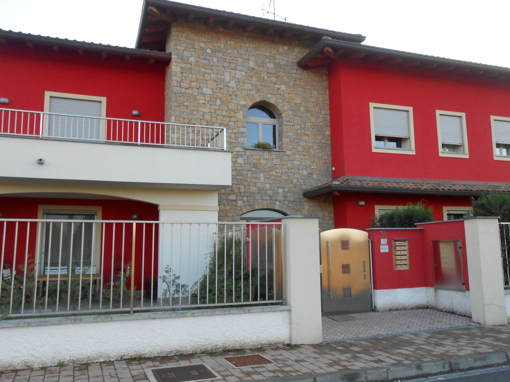 Ingresso dell’edificio con facciate rosse e corpo centrale rivestito in pietra