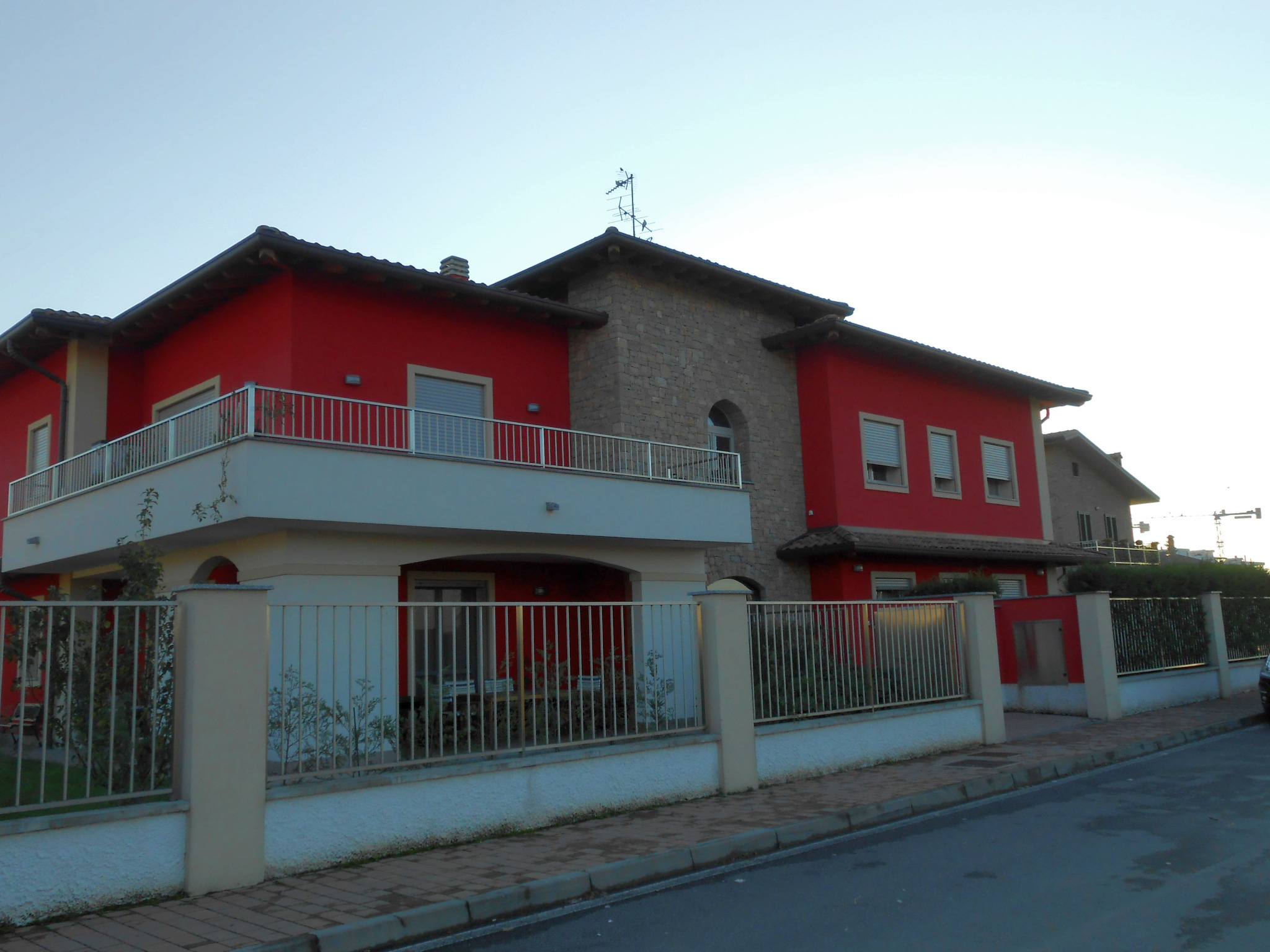 Vista generale dell’edificio residenziale rosso con volume centrale in pietra