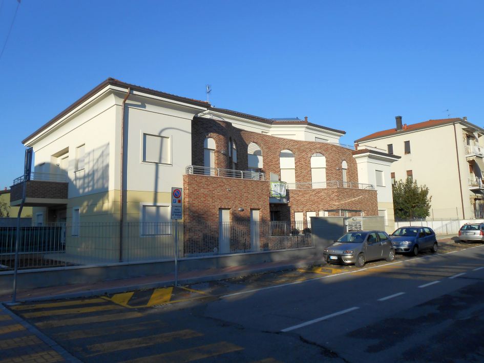 Vista urbana complessiva dell’edificio residenziale con volume curvo in laterizio