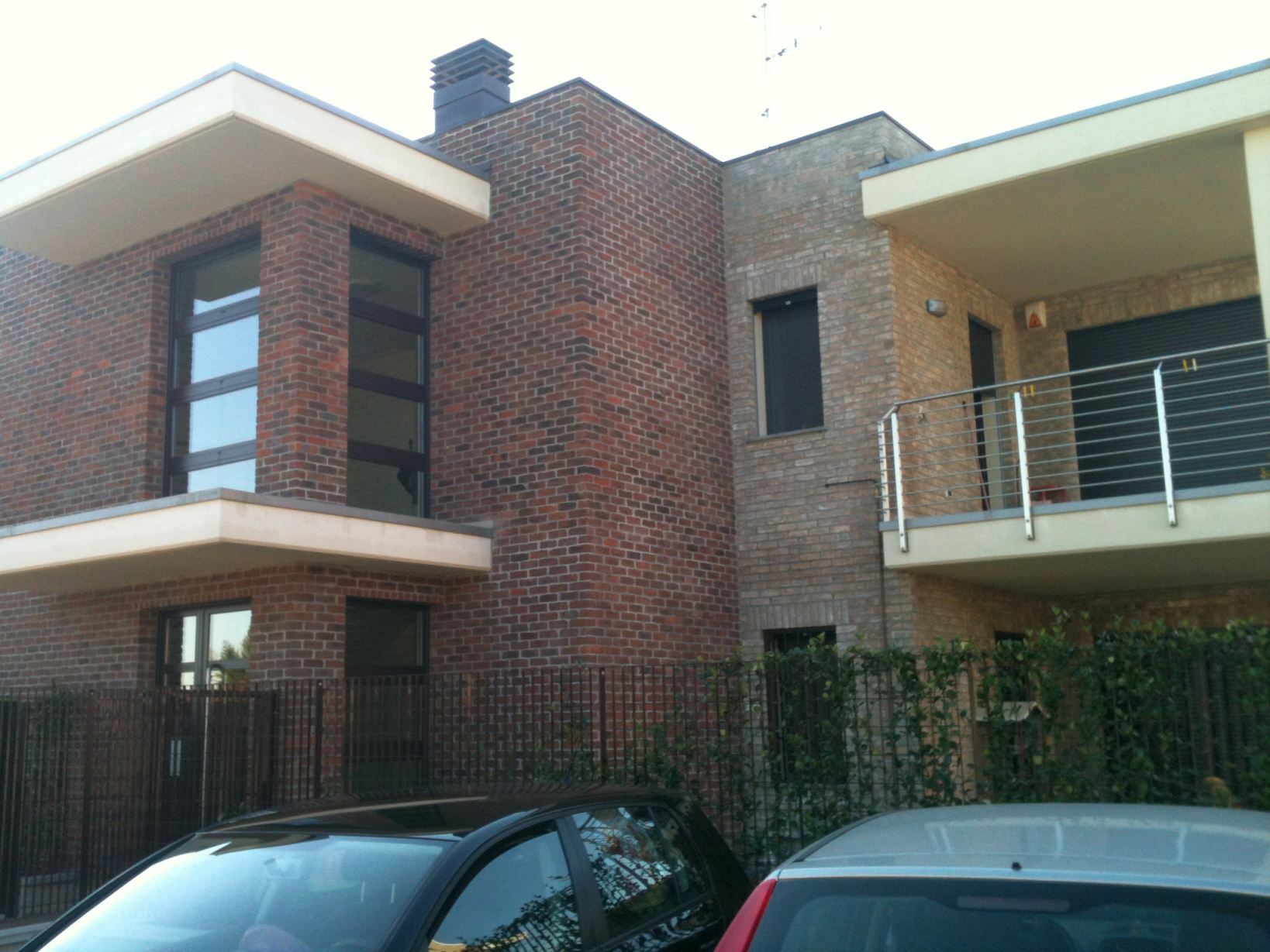Composizione residenziale in laterizio con grandi aperture e balconi