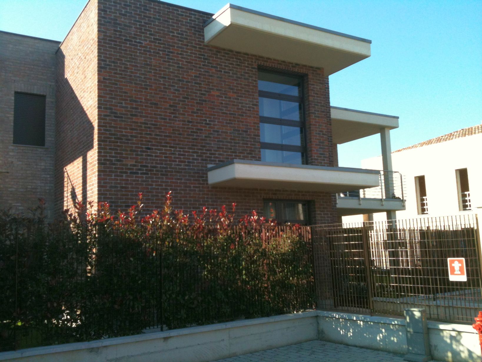 Volume in laterizio con grande apertura verticale vetrata e balcone aggettante