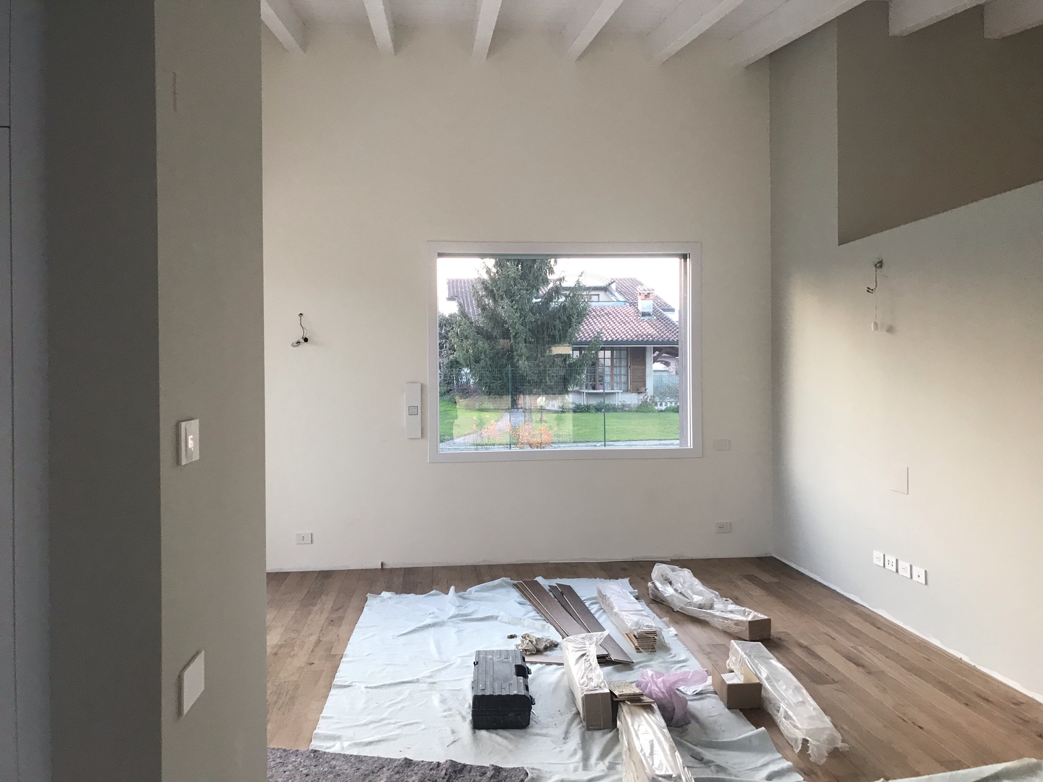 Interno luminoso con soffitto a travi e finestra sul verde