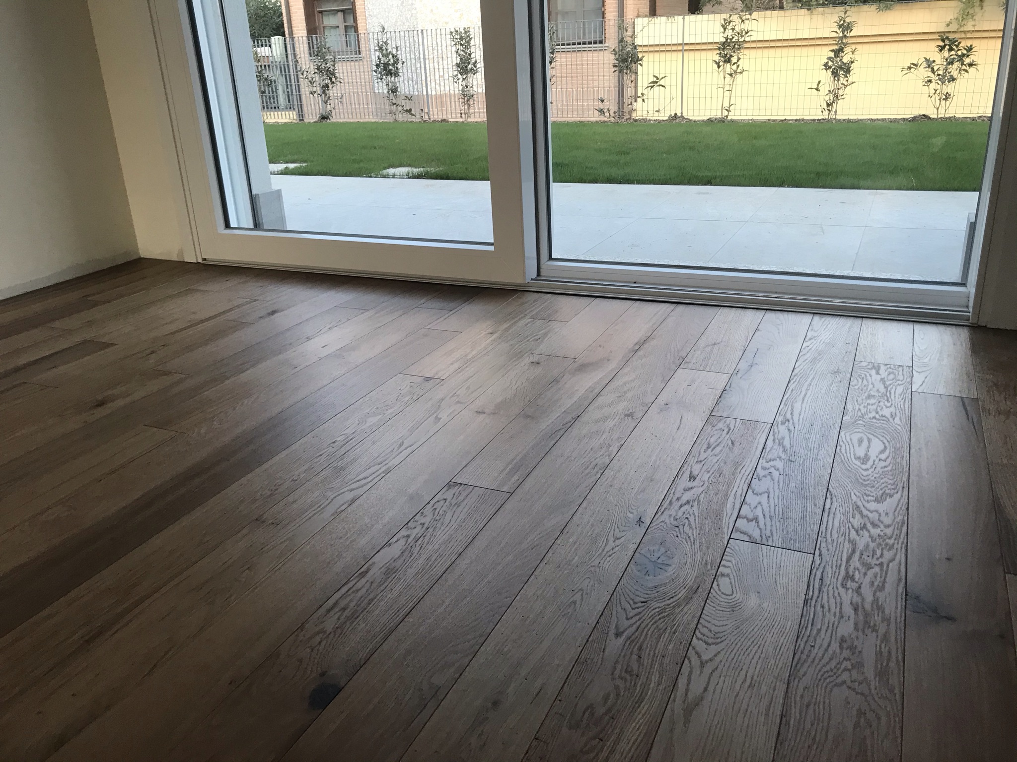 Spazio interno con pavimento in legno e grande vetrata verso il giardino