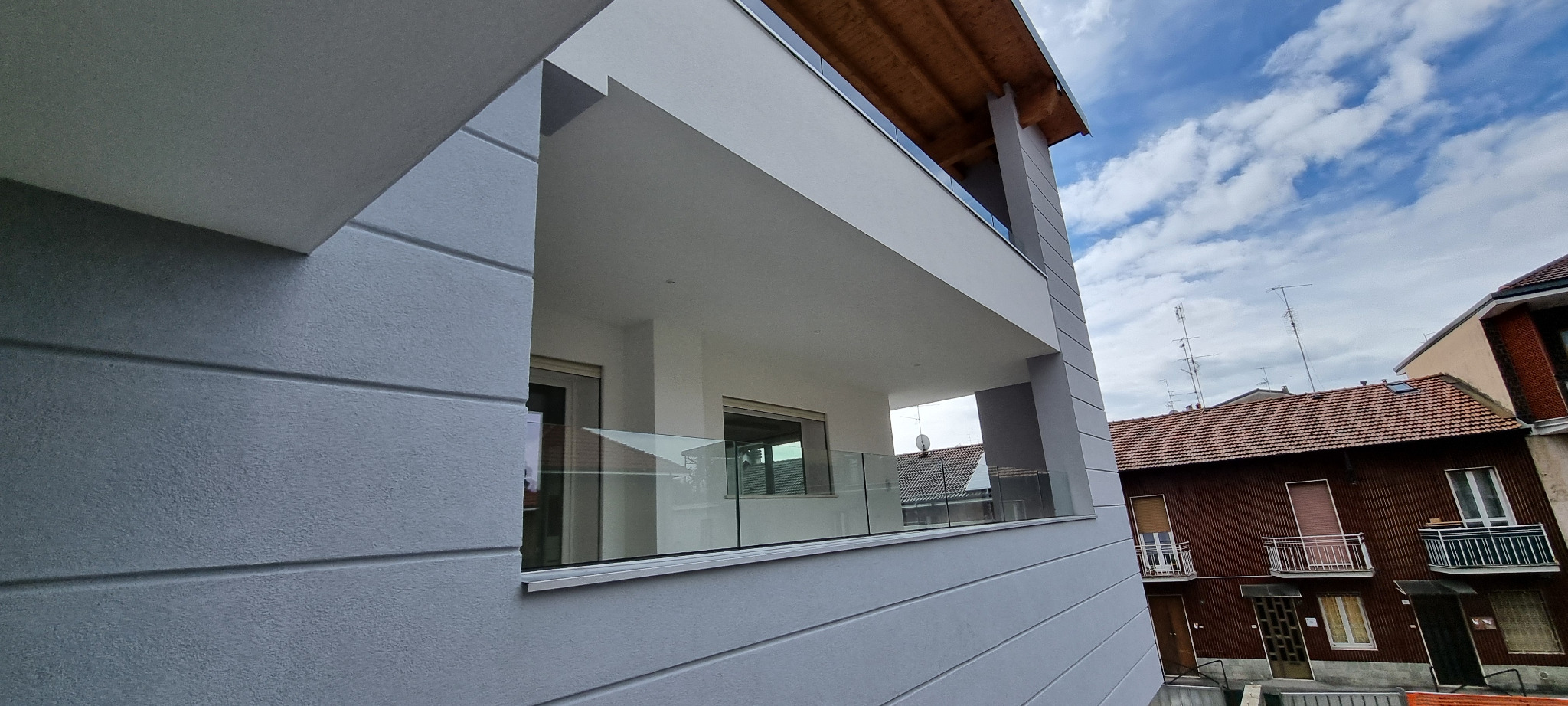 Dettaglio della loggia con parapetto trasparente e copertura in legno